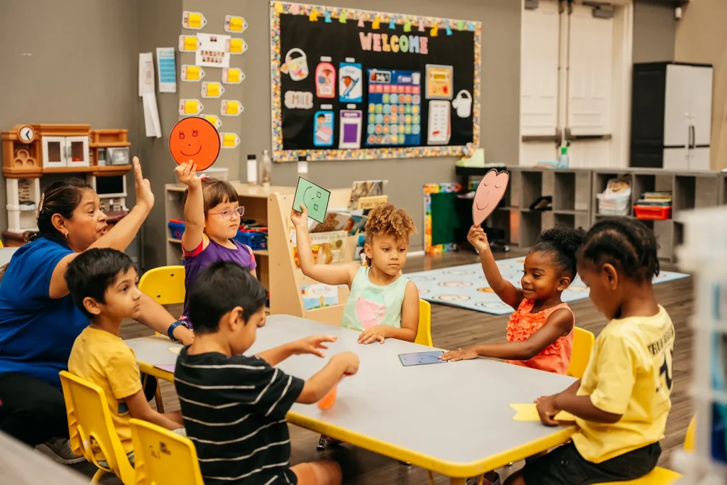children and a teacher sitting around a classroom table